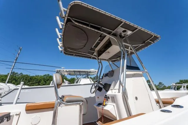 Slide: The Image of 2004 Cobia 234 boat with T-top and console, under clear blue sky. - 8