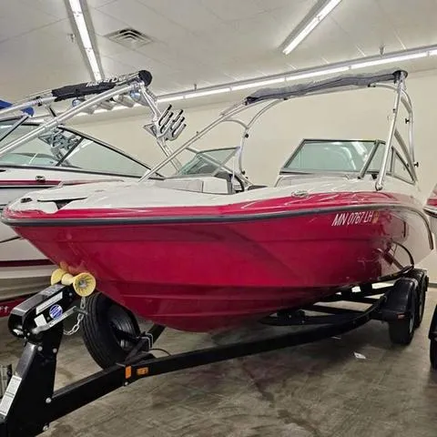 Slide: The Image of 2015 Yamaha AR210 boat, red exterior, displayed indoors on a trailer. - 3