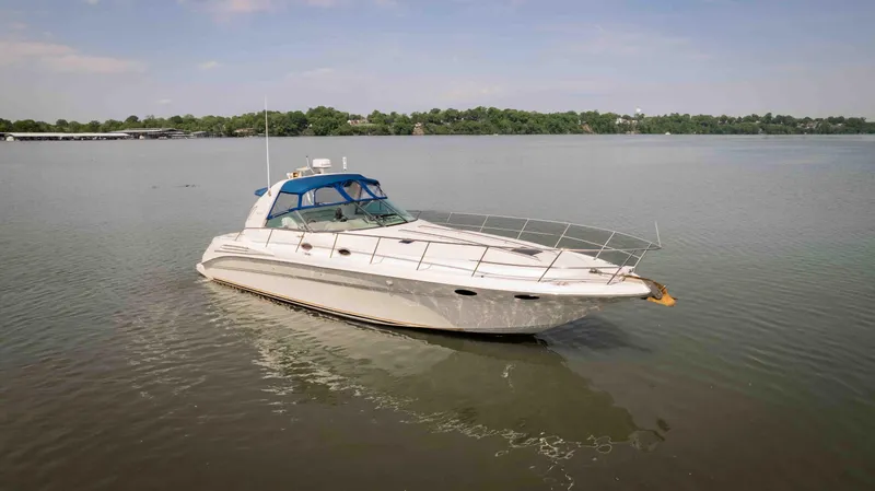 Slide: The Image of 1998 Sea Ray Sundancer 400 yacht on calm water, featuring a sleek design and blue canopy. - 11