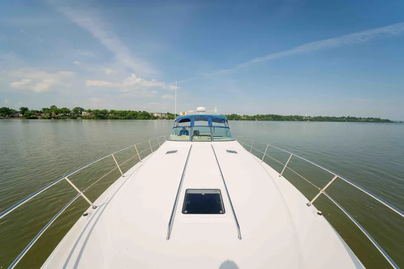 Slide: The Image of 1998 Sea Ray Sundancer 400 yacht cruising on calm waters under a clear blue sky. - 17