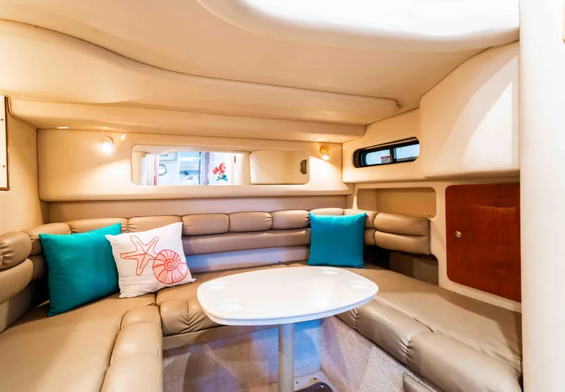 Slide: The Image of 1998 Sea Ray Sundancer 400 interior with beige seating, colorful pillows, and a white table. - 35