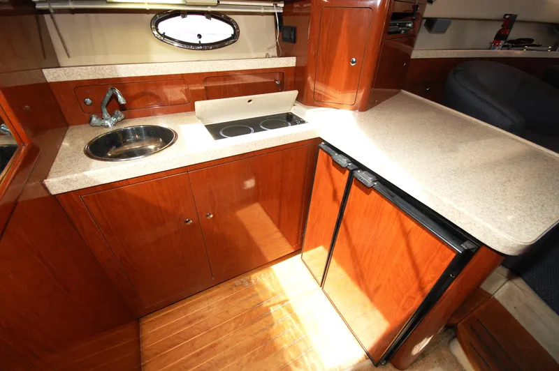 Slide: The Image of 2005 Regal Commodore 3880 yacht kitchen with wood cabinetry, sink, stove, and mini-fridge. - 24