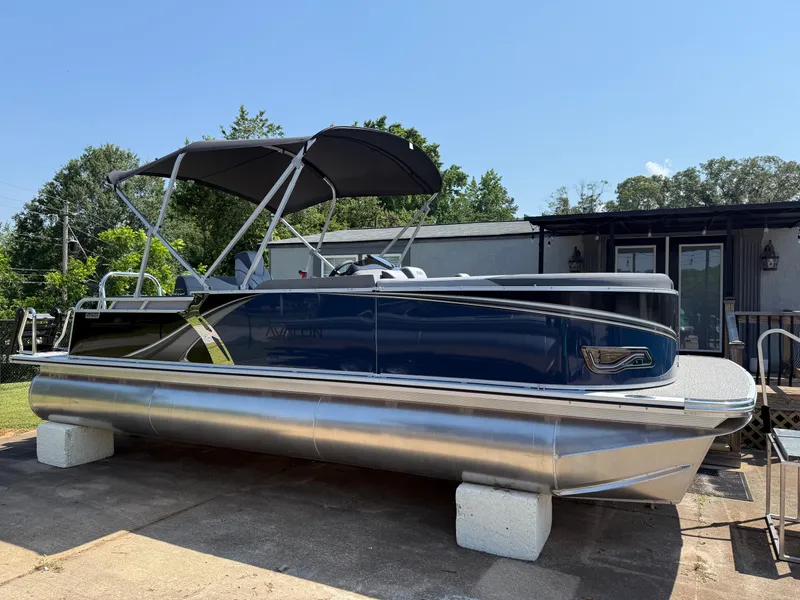 The Image of 2025 Avalon LSZ Cruise Bench pontoon boat with canopy, parked on concrete blocks. - 0