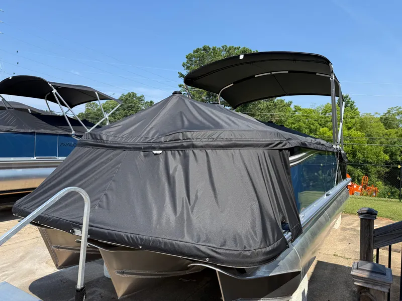 Slide: The Image of 2025 Avalon LSZ Cruise Bench pontoon boat with black cover, parked outdoors. - 5