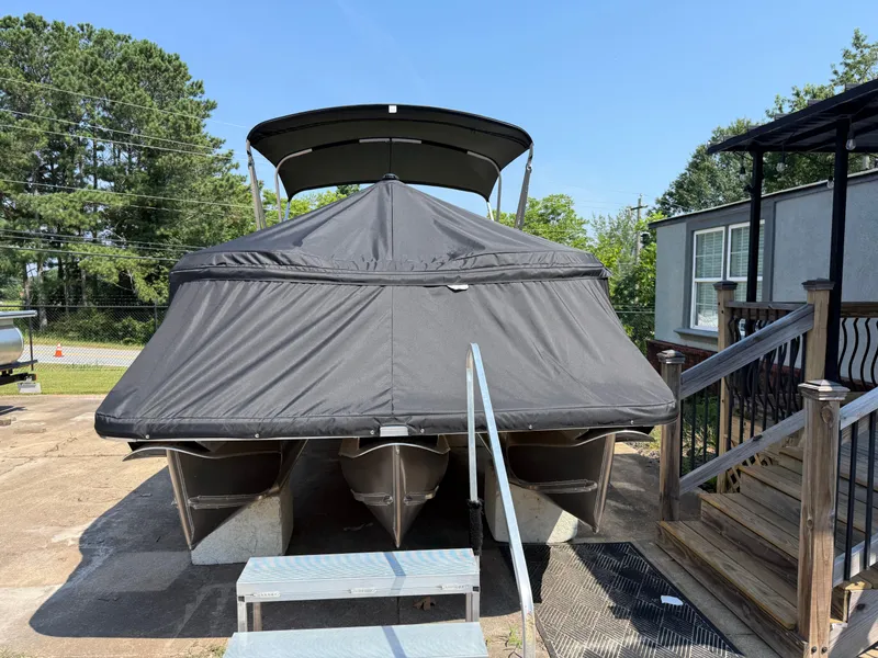 Slide: The Image of 2025 Avalon LSZ Cruise Bench pontoon boat covered, parked near wooden steps. - 6