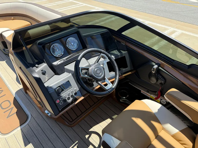 Slide: The Image of 2025 Avalon Catalina Quad Lounger Windshield boat dashboard with steering wheel and controls. - 23