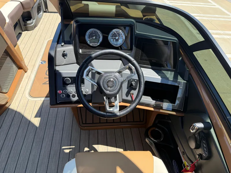 Slide: The Image of 2025 Avalon Catalina Quad Lounger Windshield boat dashboard with steering wheel and controls. - 24