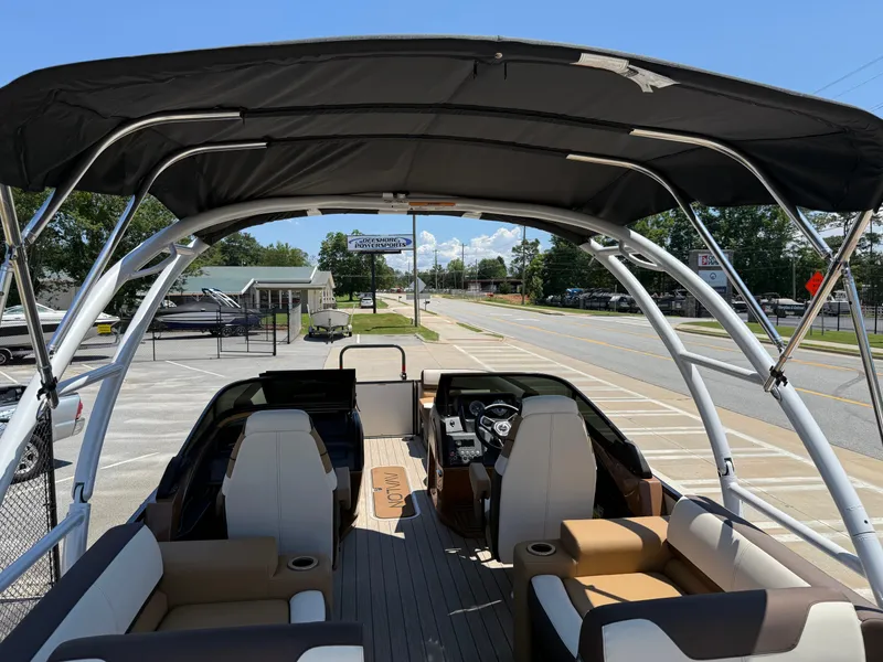 Slide: The Image of 2025 Avalon Catalina Quad Lounger Windshield boat with spacious seating and canopy, parked outdoors. - 39
