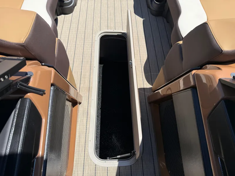 Slide: The Image of 2025 Avalon Catalina Quad Lounger Windshield interior storage compartment, open between brown seats. - 47