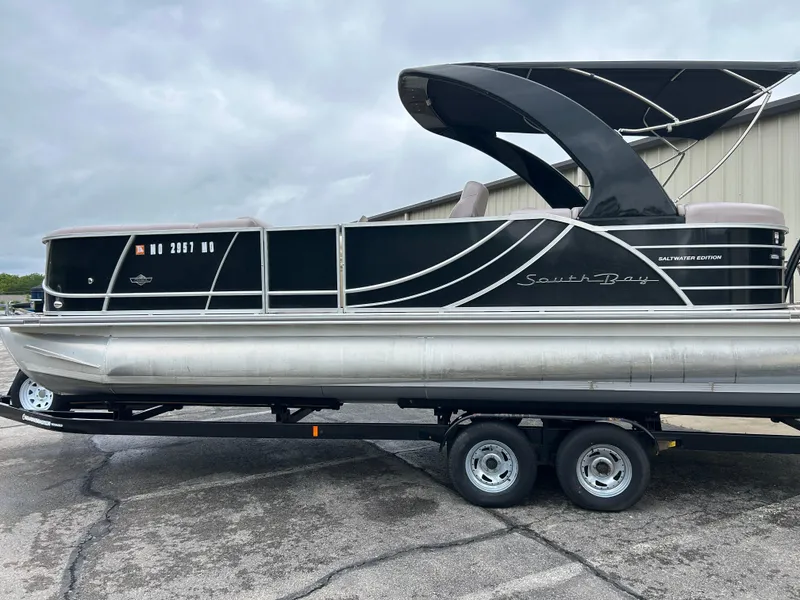 Slide: The Image of 2017 South Bay 525 RS Arch 3.0+ pontoon boat on trailer, parked outdoors. - 0