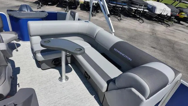 Slide: The Image of 2025 Bennington 20 SF Fish pontoon boat with gray seating and table, docked outdoors. - 16
