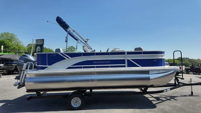Slide: The Image of 2025 Bennington 20 SF Fish pontoon boat on trailer, blue and silver design, sunny day. - 6