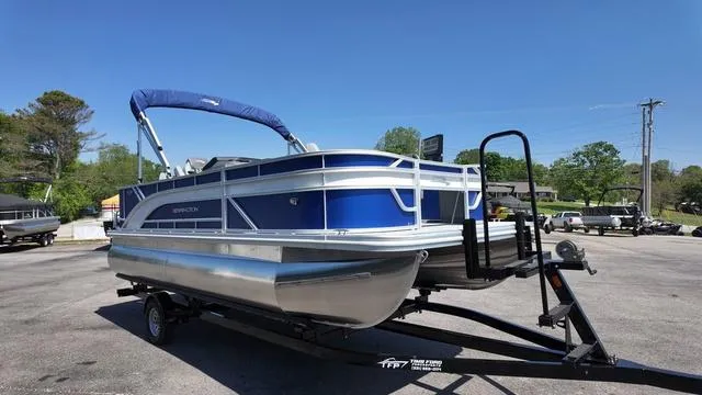 Slide: The Image of 2025 Bennington 20 SF Fish pontoon boat on trailer, blue and silver design, sunny day. - 7