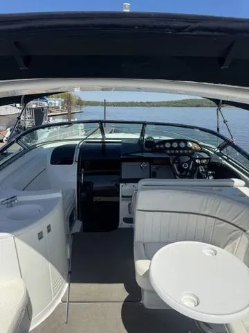 Slide: The Image of 2003 Cobalt 360 boat interior with seating and steering, docked by a serene lake. - 7