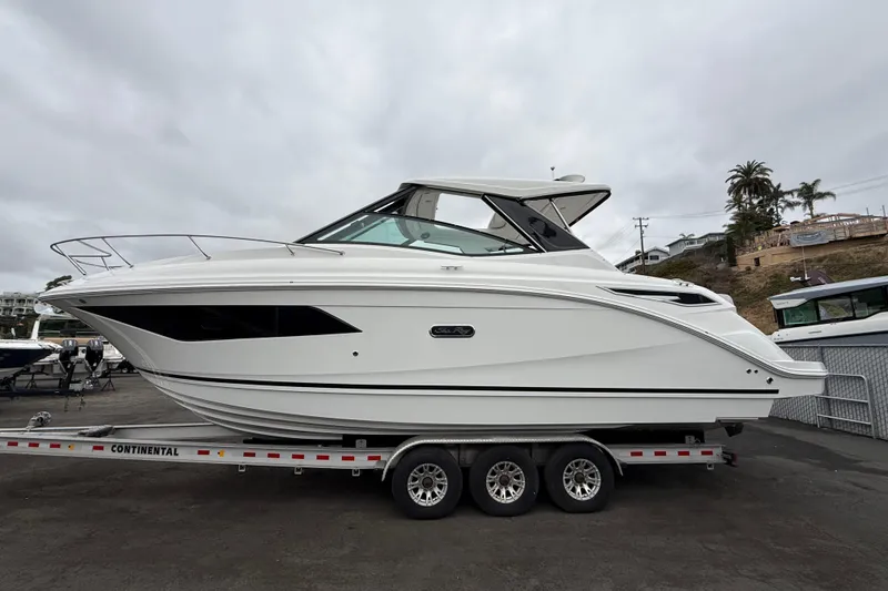 The Image of 2026 Sea Ray Sundancer 320 boat on trailer, side view, overcast sky. - 0