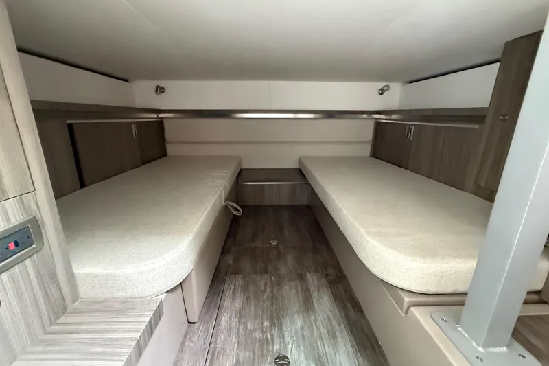 Slide: The Image of 2026 Sea Ray Sundancer 320 cabin interior with twin beds and modern wood finish. - 18