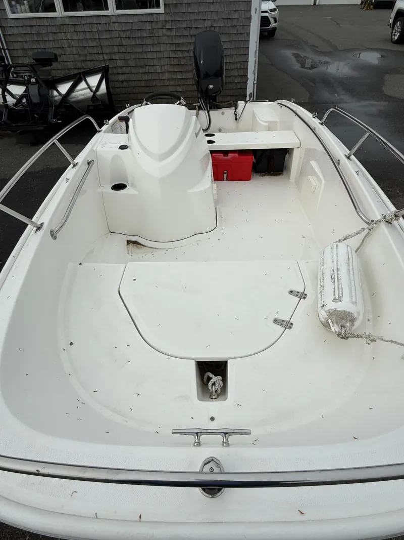 Slide: The Image of 2016 Boston Whaler 150 Super Sport boat interior with white seating and red storage box. - 12