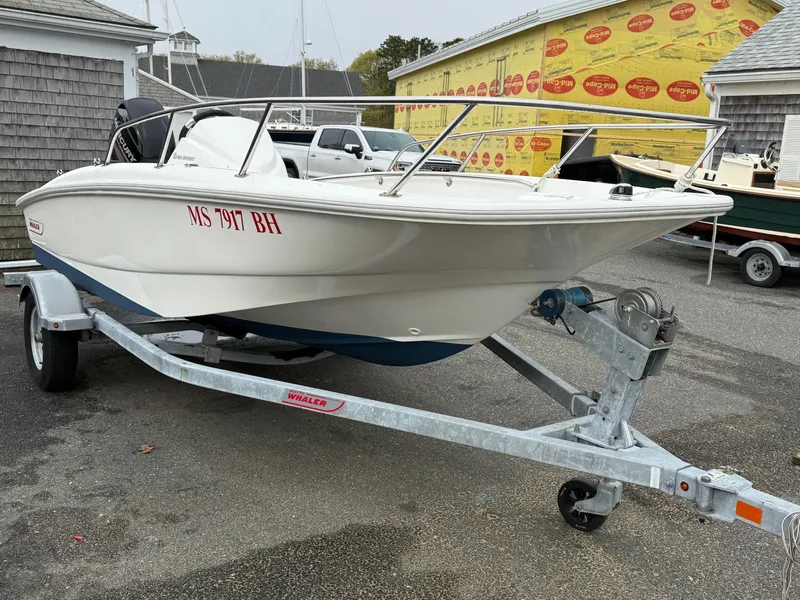 Slide: The Image of 2016 Boston Whaler 150 Super Sport boat on trailer in a parking lot. - 2