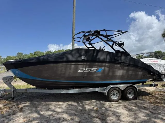 Slide: The Image of 2022 Yamaha Boats 255XD on trailer, black hull, parked outdoors under blue sky. - 1