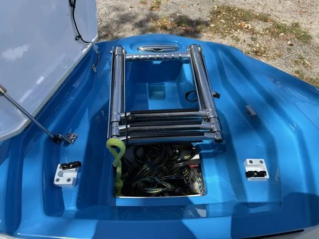 Slide: The Image of 2022 Yamaha Boats 255XD with open storage compartment and ladder on blue deck. - 12
