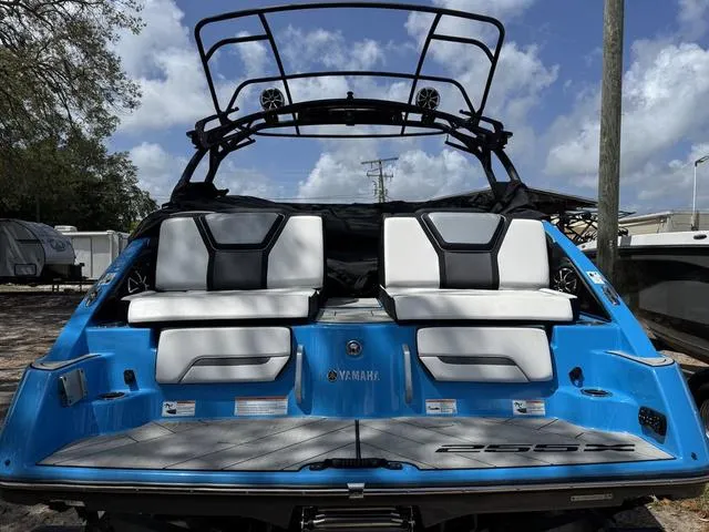Slide: The Image of 2022 Yamaha Boats 255XD, blue exterior, rear view with seating and wakeboard tower. - 2