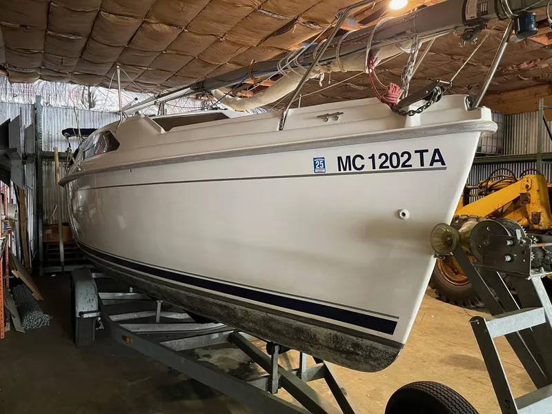 Slide: The Image of 2002 Hunter 260 sailboat on trailer in storage, side view with visible registration number. - 35