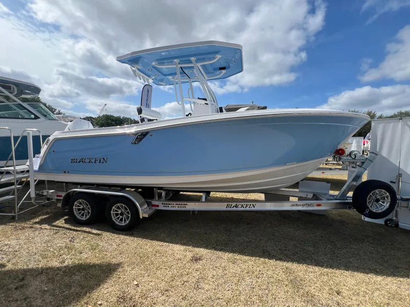 The Image of 2025 Blackfin 222 CC boat on trailer, displayed outdoors under cloudy sky. - 0