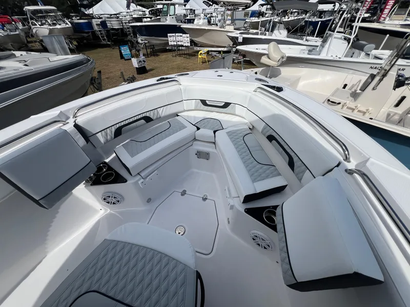 Slide: The Image of 2025 Blackfin 222 CC boat interior with cushioned seating and modern design at a boat show. - 13
