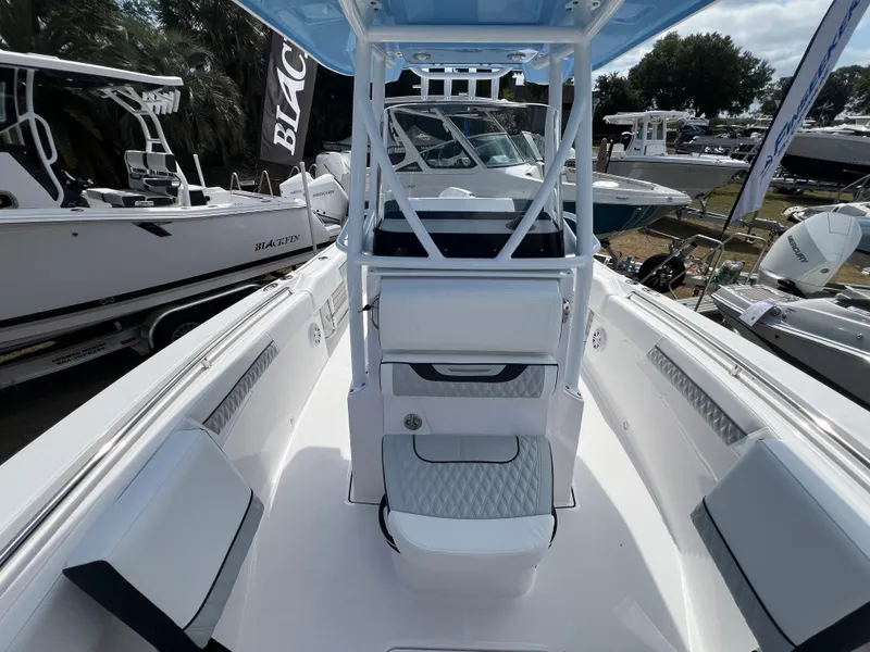 Slide: The Image of 2025 Blackfin 222 CC boat interior with seating and console, displayed at a boat show. - 14
