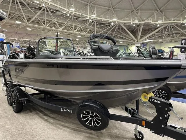 Slide: The Image of 2025 Lund 1975 Tyee Sport boat on display in showroom, featuring sleek design and modern features. - 1