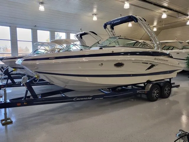 Slide: The Image of 2024 Crownline E260 XS boat displayed indoors on a trailer. - 1
