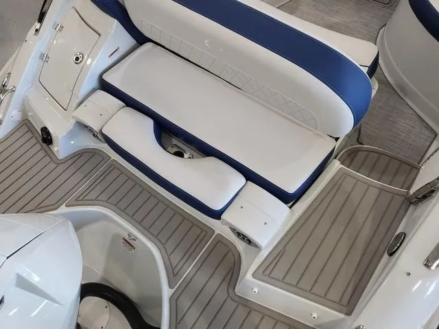 Slide: The Image of 2024 Crownline E260 XS boat interior with white and blue seating and gray flooring. - 5