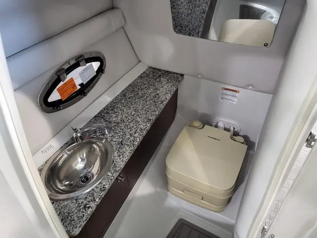 Slide: The Image of 2024 Crownline E260 XS boat interior with sink, granite countertop, and portable toilet. - 9
