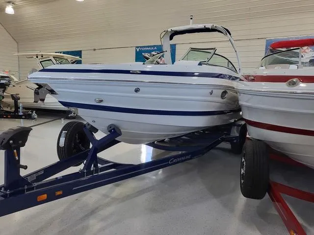 Slide: The Image of 2024 Crownline 280 SS boat on trailer in showroom, featuring sleek design and blue accents. - 2