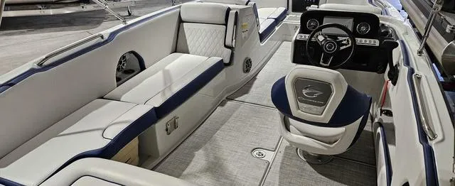 Slide: The Image of 2024 Crownline E230 XS boat interior with plush seating and modern dashboard. - 3