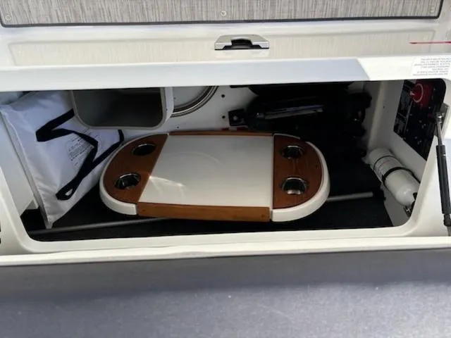 Slide: The Image of Storage compartment in a 2021 Cobalt R8 boat with a wooden table and accessories. - 10