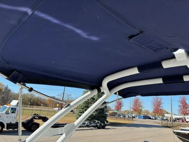 Slide: The Image of 2021 Cobalt R8 boat canopy with blue fabric and white frame, parked outdoors. - 18