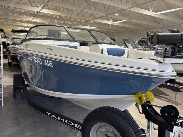 Slide: The Image of 2021 Tahoe 450 TF boat in showroom, blue and white exterior, on trailer. - 2