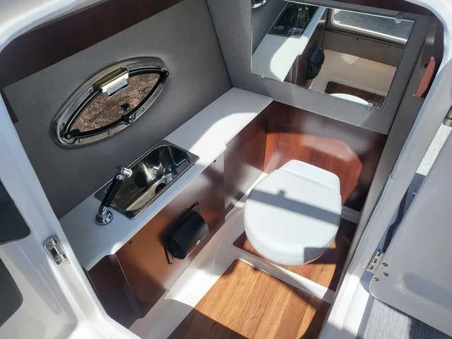 Slide: The Image of 2022 Chaparral 28 Surf boat interior bathroom with sink, toilet, and mirror. - 10