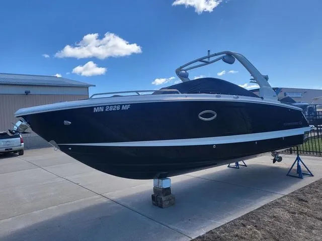 Slide: The Image of 2022 Chaparral 28 Surf boat on display, sleek design, parked outdoors under blue sky. - 6