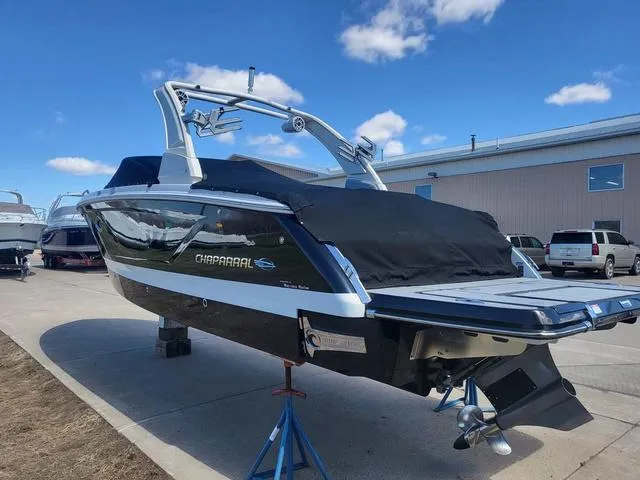 Slide: The Image of 2022 Chaparral 28 Surf boat on display, black cover, outdoor setting. - 7