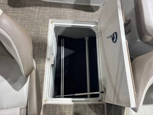 Slide: The Image of 2019 Crownline E 215 XS boat storage compartment with open hatch and beige seating. - 14