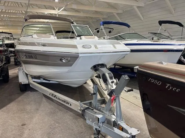 Slide: The Image of 2019 Crownline E 215 XS boat on trailer in indoor showroom. - 2