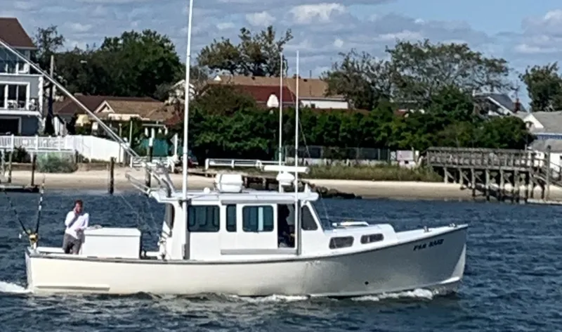 The Image of 1998 Northern Bay Pilothouse 36 boat cruising near a coastal residential area. - 0