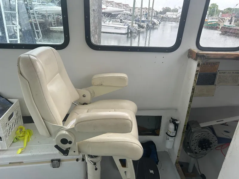 Slide: The Image of White captain's chair inside a 1998 Northern Bay Pilothouse 36 boat, overlooking marina. - 13