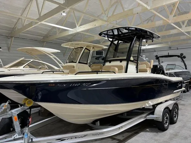 Slide: The Image of 2025 Scout 215 XSF boat in showroom, navy hull, on trailer. - 1