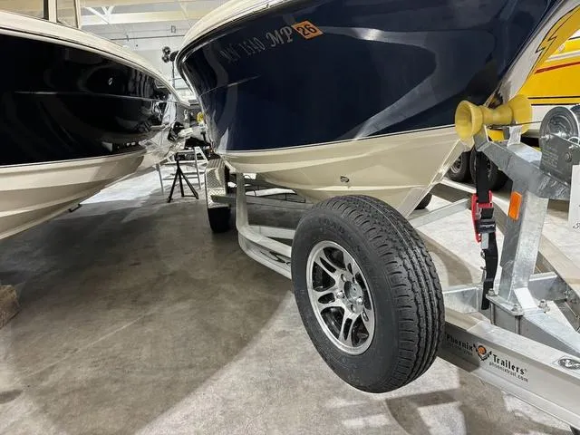 Slide: The Image of 2025 Scout 215 XSF boat on trailer in showroom, showcasing sleek design and modern features. - 13