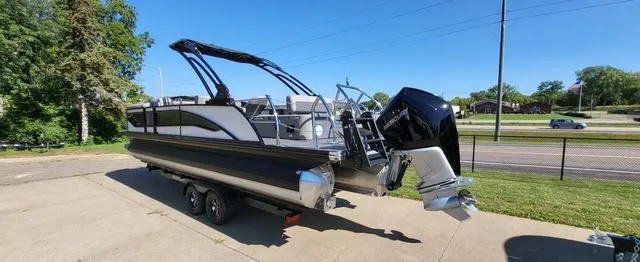 Slide: The Image of 2024 Barletta Corsa 25UEA pontoon boat on trailer, parked outdoors. - 2