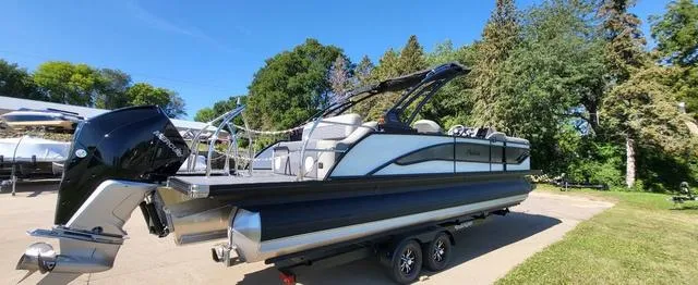 Slide: The Image of 2024 Barletta Corsa 25UEA pontoon boat on trailer, parked outdoors. - 4