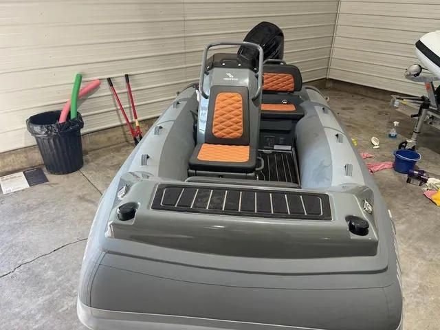 Slide: The Image of 2023 Highfield Sport 390 inflatable boat in a garage, featuring orange and gray seating. - 9